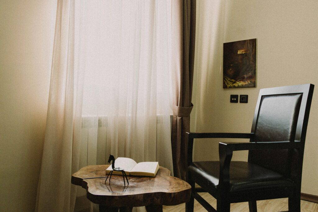 A tranquil reading corner with a chair, table, and book by a sunlit window.