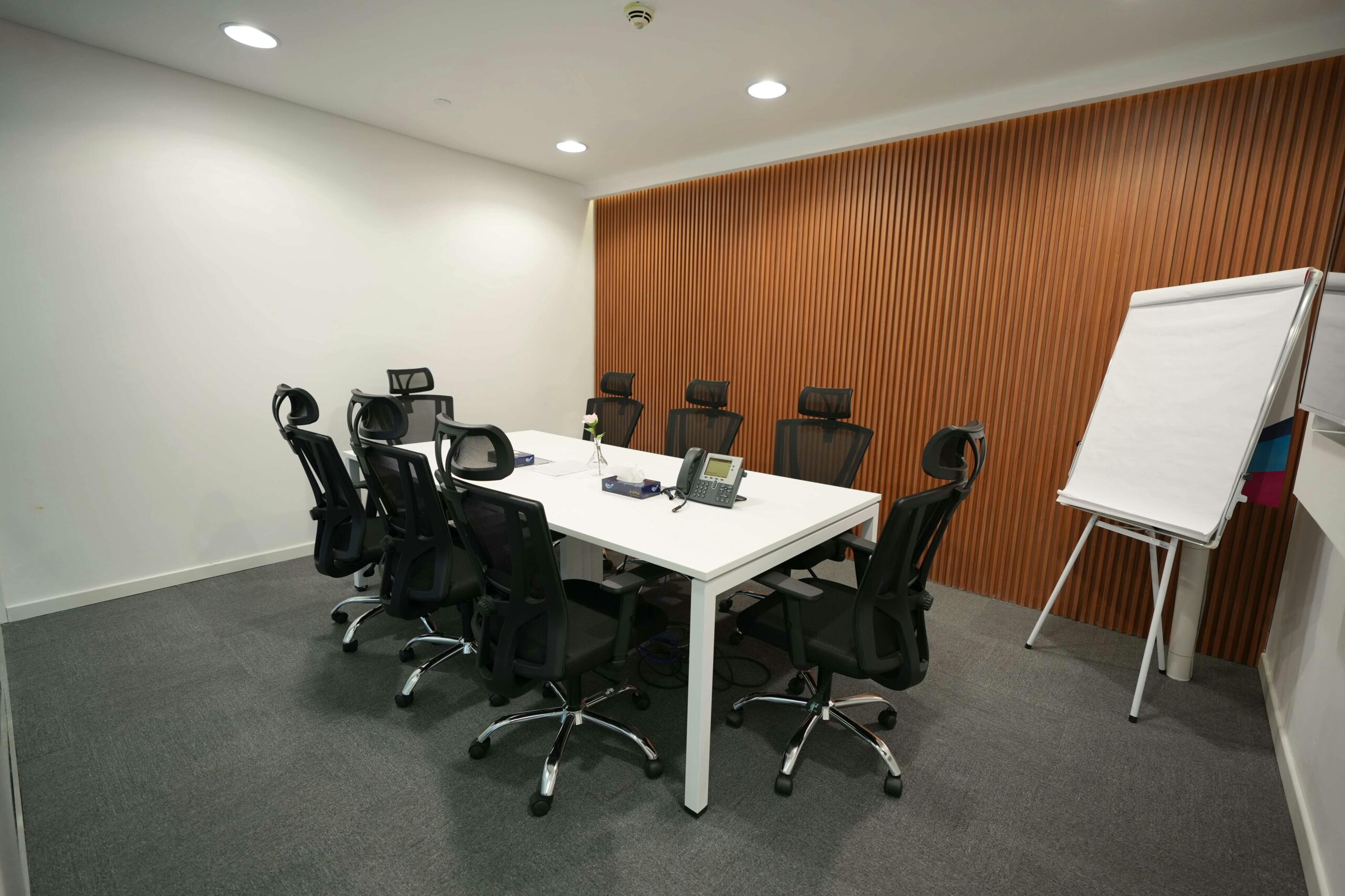 Spacious meeting room featuring ergonomic chairs, a large table, and a flip chart.